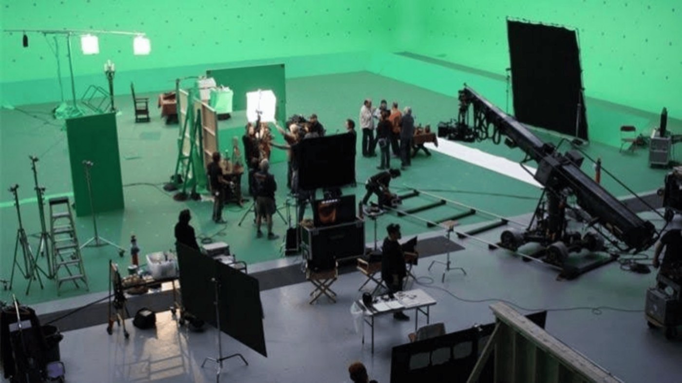 Enorme groene filmhal met een kraan, lampen en een crew
