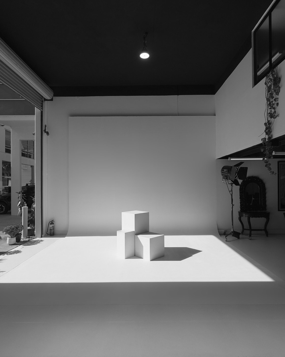 Witte hoekloze wand met twee witte blokken en een lamp op statief