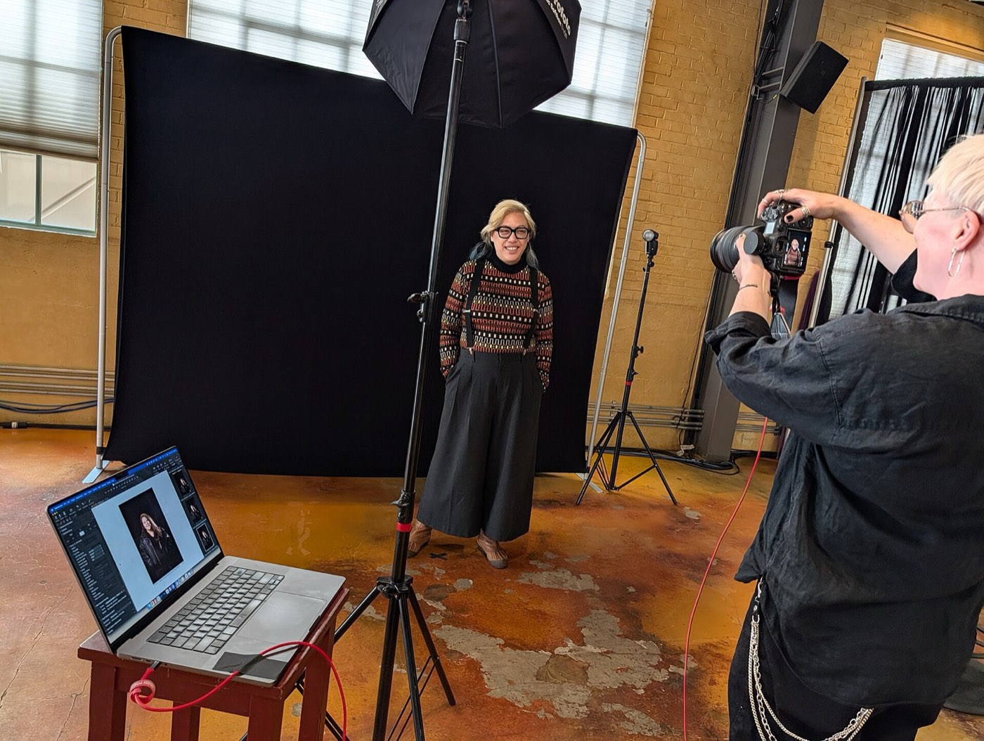 Een fotograaf maakt een portret voor een zwart doek met een softbox